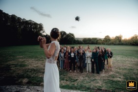At Domaine de Neuville, Yvelines, France, a beautiful bride tosses her bouquet to a group of excited girls eagerly waiting to be married.